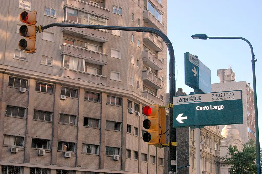 Semáforo y cartel de calle Cerro Largo en una esquina del barrio Centro, Montevideo, con edificio de apartamentos de fondo