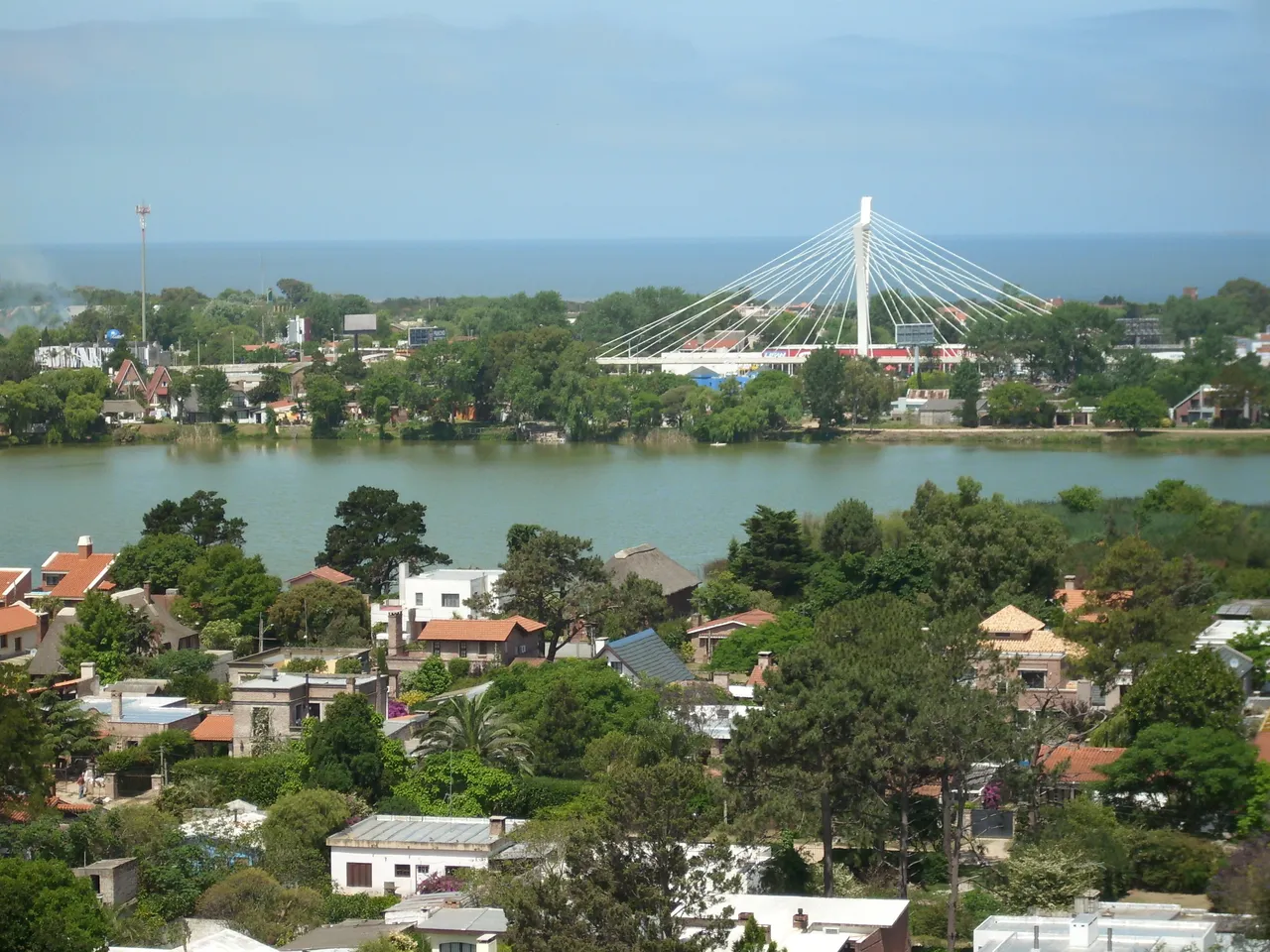 Vista elevada de Barra de Carrasco con el puente de Las Américas sobre el arroyo Carrasco, casas y el mar de fondo, en Ciudad de la Costa, Canelones