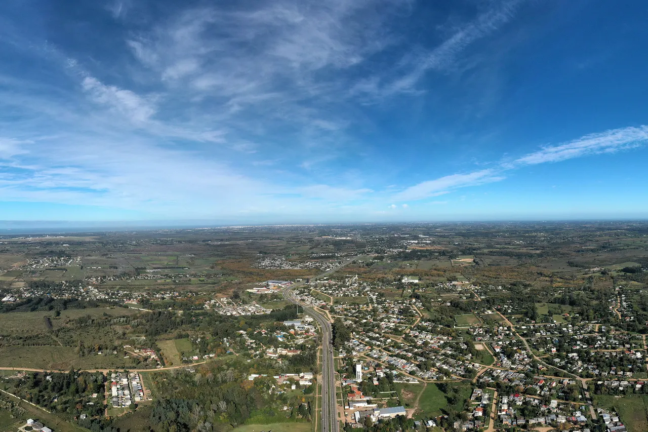 Vista aérea de Barros Blancos, Canelones, con la trama de casas bajas a ambos lados de la ruta