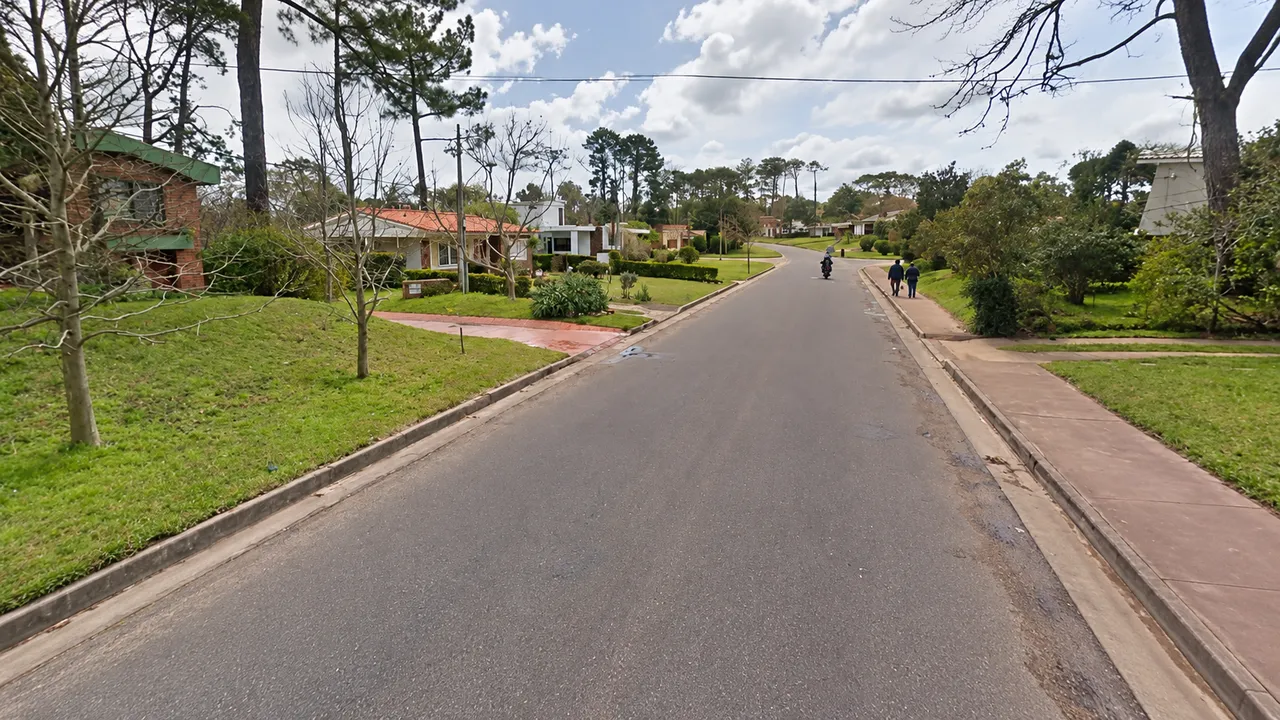 Calle residencial con chalets de techo de tejas entre jardines y pinos en Beaulieu, Piriápolis, Maldonado