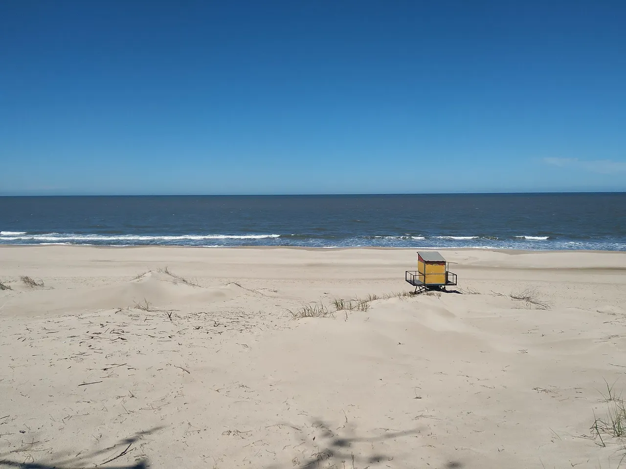 Baliza de guardavidas amarilla sobre dunas vacías en la playa de Parque del Plata Sur, con cielo despejado