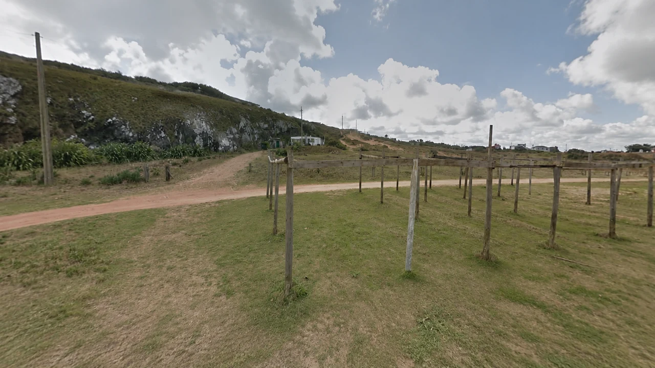 Acceso entre ladera rocosa y pasto en Playa las Grutas, Punta Ballena, Maldonado